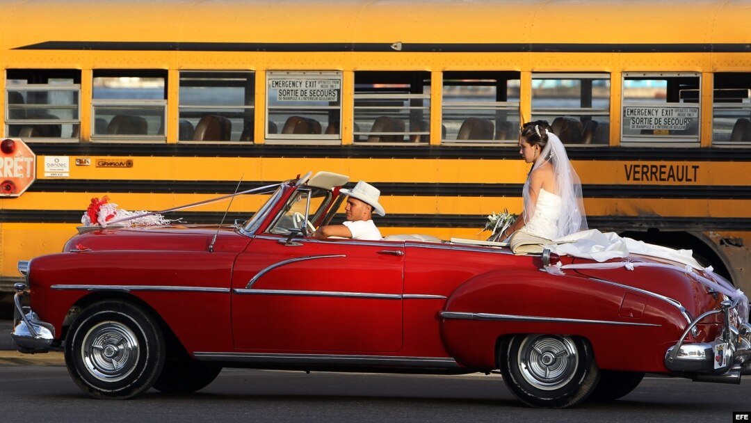 Una pareja de recién casados viaja en un viejo auto descapotable. 