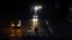 Transeúntes cruzan a oscuras el lunes una calle de Caracas, iluminados solamente por los focos de un vehículo (Foto: AFP).