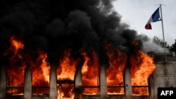 Las llamas arrasan la oficina de turismo de Lyon después de que fuera incendiada por manifestantes durante una protesta contra el "alto costo de vida", en Lyon, sureste de Francia, el 17 de octubre de 2026.