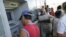 Un residente local extrae dinero de un cajero automático mientras otros hacen fila.