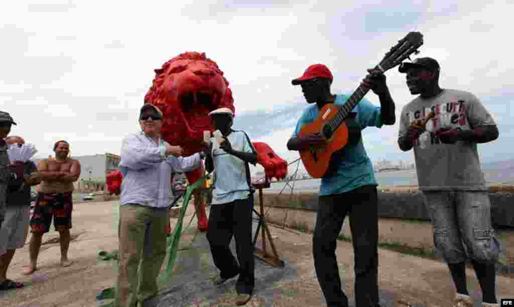 El artista pl&aacute;stico cubano Roberto Fabelo (i) posa junto a un le&oacute;n rojo creado por &eacute;l que conforma la obra "Garras en la piedra" que se instala en los arrecifes del malec&oacute;n de La Habana (Cuba). Esta pieza forma parte 