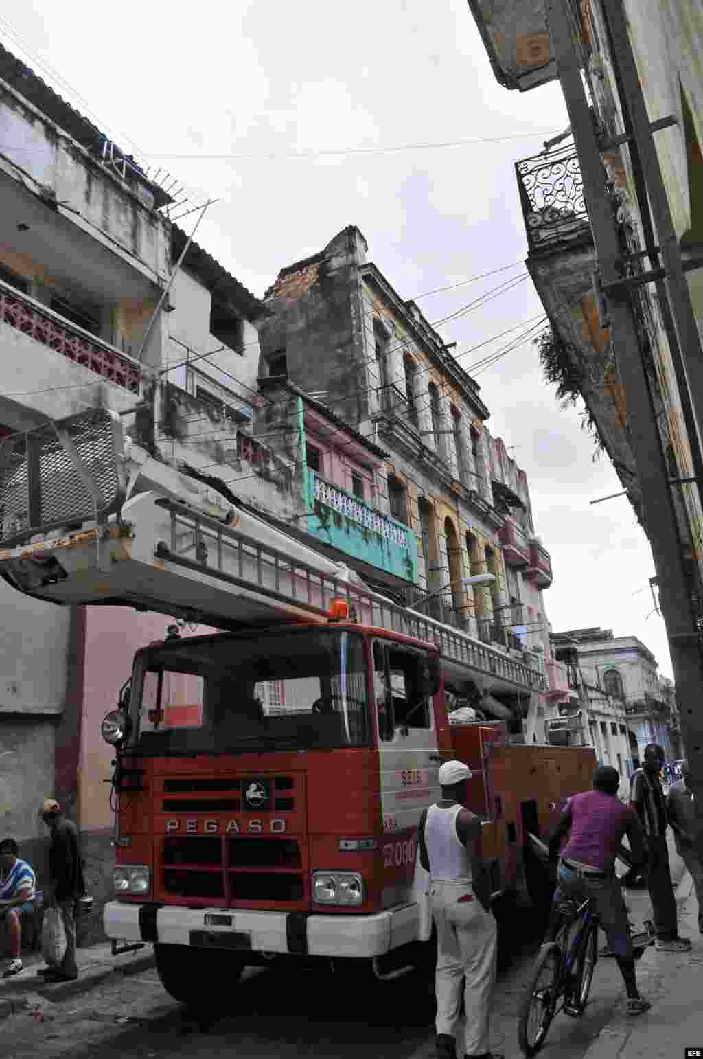  Varias personas pasan al lado de un camión estacionado frente a un edificio derrumbado parcialmente debido a las fuertes lluvias y que se encuentra ubicado en el barrio de Centro Habana.