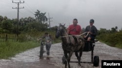 Los hombres viajan en su carro tirado por caballos por una carretera inundada mientras el huracán Helene pasa cerca de la costa cubana, en Pinar del Río, Cuba, el 25 de septiembre de 2024. REUTERS/Stringer