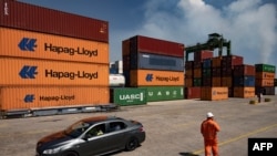 A worker stands in front of containers in the container terminal in the port of Mariel, Artemisa Province, Cuba, on September 20, 2023. (Photo by Yamil LAGE / AFP)