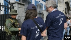 Observadores del Centro Carter presentan sus credenciales a un soldado en una mesa de votación, el 28 de julio de 2024 en Caracas. (AFP/Yuri Cortez).