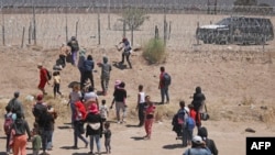 Migrantes que buscan ingresar a Estados Unidos intentan cortar una cerca de alambre de púas instalada por la Guardia Nacional de Texas en la frontera con Ciudad Juárez, estado de Chihuahua, México, el 13 de mayo de 2024. (Foto de HERIKA MARTINEZ / AFP)