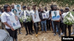 Familiares de las víctimas de un ataque perpetrado por una banda armada el 23 de agosto de 2026 sostienen sus fotografías durante funeral celebrado en Kenscoff, Haití. REUTERS/Patrice Noel