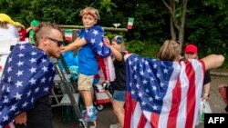 Familias portan la bandera de los Estados Unidos la víspera de la celebración por el Día de la Independencia, en Gloucester, Massachusetts, el 3 de julio de 2023. (Photo by Joseph Prezioso / AFP)