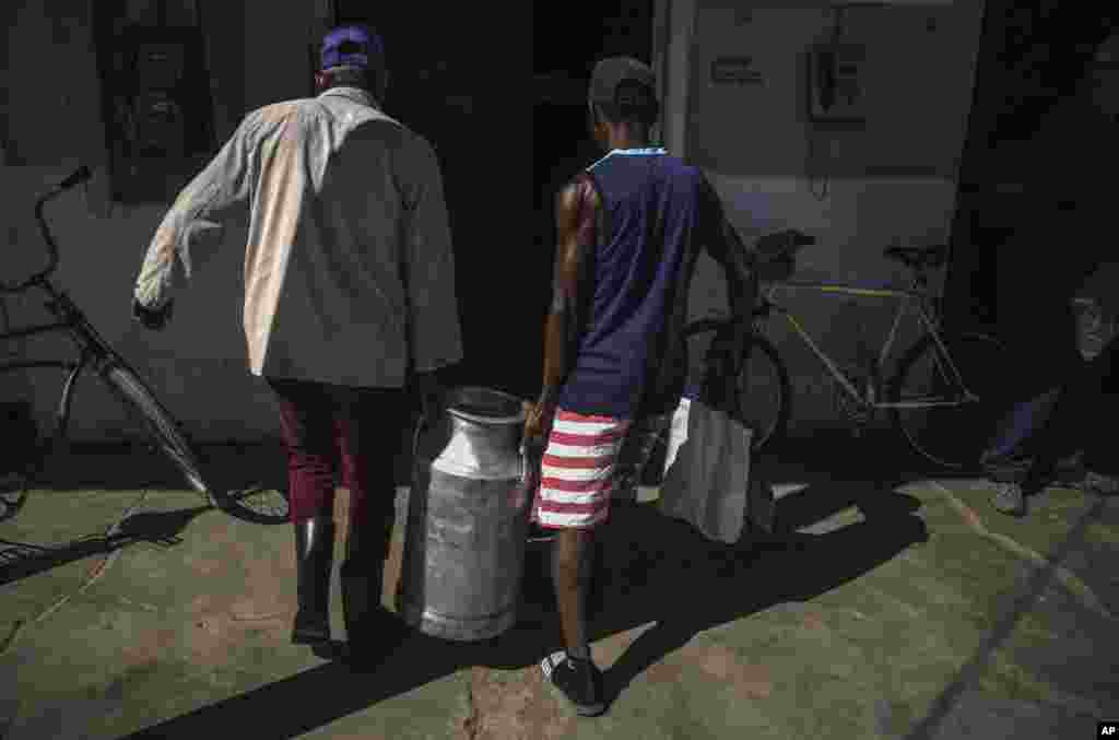 Cubanos transportan un tanque de leche en San Nicolás. El régimen dice que&nbsp; le cuesta entre 1.500 y 1.600 millones de dólares mantener la canasta familiar normada, pues casi toda está sustentada sobre la importación de productos o de insumos para la producción.