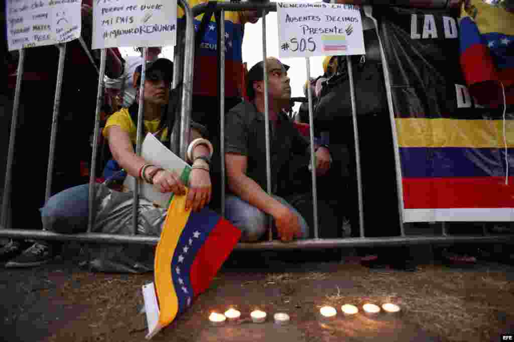 Manifestantes sostienen pancartas hoy, jueves 12 de febrero de 2015, durante una movilización en contra del Gobierno de Nicolás Maduro frente a la Embajada de Venezuela, en Santiago (Chile). En el aniversario de las primeras manifestaciones estudiantiles 