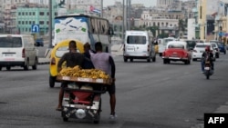 Tres hombres transportan plátanos en un bicitaxi, en La Habana, el 18 de julio de 2023. (Photo by YAMIL LAGE / AFP)