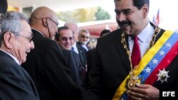  Fotografía cedida por Prensa Miraflores del presidente de Venezuela, Nicolás Maduro (d), saluda a Raúl Castro durante el desfile militar para conmemorar el primer aniversario del la muerte del fallecido mandatario venezolano Hugo Chávez.