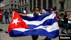 Un hombre sostiene una bandera cubana durante una manifestación en apoyo de las protestas contra el gobierno en Cuba, frente al parlamento español en Madrid, España, el 12 de julio de 2021. 