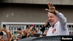El actual presidente, Luiz Inácio Lula Da Silva, saluda a sus seguidores, tras votar en Sao Paulo.