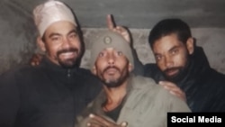 Yoandry Rosabal Arias con un abrigo negro junto a otros dos cubanos en Rusia. 