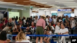 Los viajeros esperan en las puertas del aeropuerto de Linate en Milán, Italia, el viernes 19 de julio de 2024. (Foto AP/Luca Bruno)