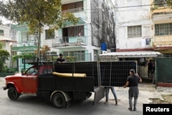 Davianis Deyunde y Julio Pérez descargan paneles solares recién adquiridos en La Habana, Cuba, 4 de febrero de 2026. REUTERS/Norlys Pérez