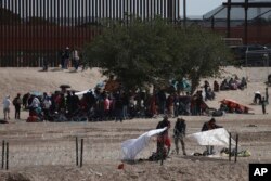 Migrantes acampados entre las alambradas y el muro fronterizo en El Paso, Texas. (AP Photo/Christian Chavez)