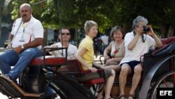 Un grupo de turistas pasea en coche por una calle de La Habana.