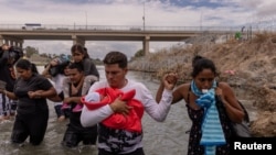 Yusniel, un cubano de 34 años y su esposa Yanara, de 30 años, fueron fotografiados mientras cruzaban la frontera de México y EEUU con su bebé de diez días de nacido, atravesando el río Grande en Eagle Pass, Texas, el 6 de octubre de 2023.