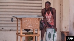 Un vendedor ambulante permanece junto a un puesto que anuncia pollo en La Habana, el 17 de octubre de 2026.  YAMIL LAGE / AFP)
