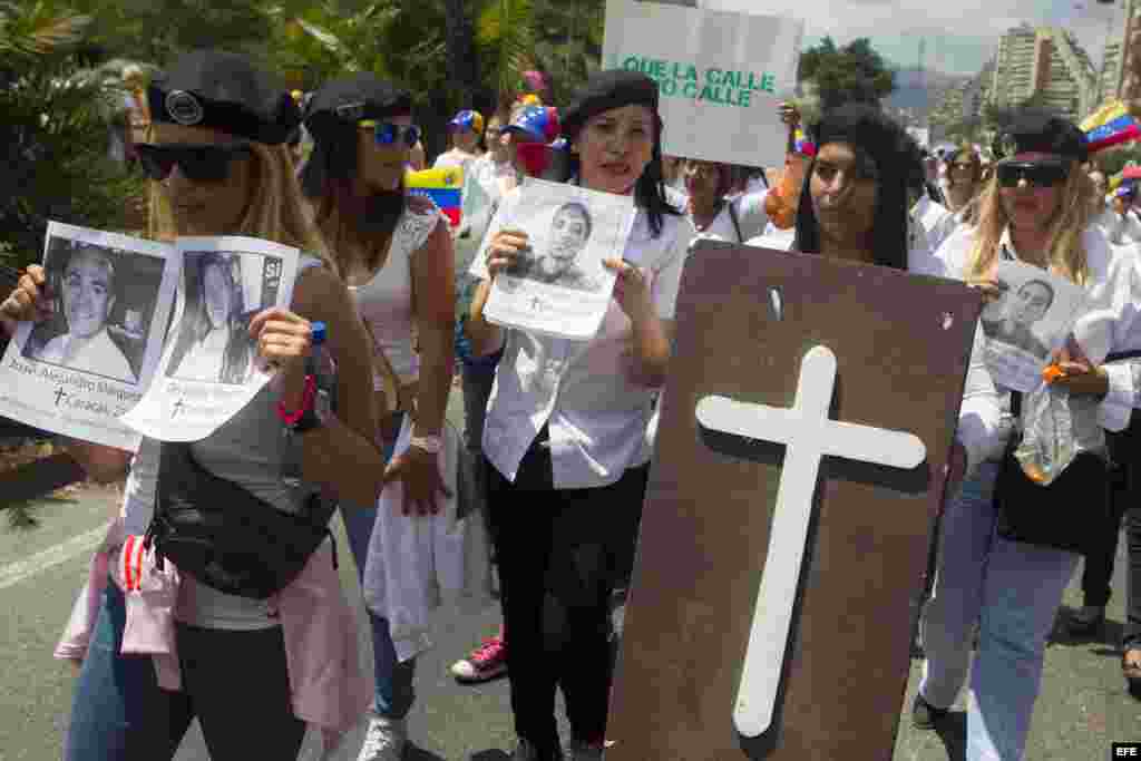 Un grupo mujeres sostiene fotografías de los rostros de las víctimas fatales de las protestas en Venezuela