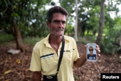 Bárbaro Falcón, quien perdió a un hijo en un barco migrante casero en algún lugar entre Cuba y el sur de Florida, posa para una foto con una foto suya en Palma Sola, Cuba, el 19 de junio de 2024. REUTERS/Alexandre Meneghini