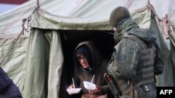 Migrantes ilegales reciben alimentos en la frontera entre Polonia y Bielorrusia. (AFP/Andrei Pokumeiko).