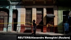 Una mujer pasa frente a varias casas en cuarentena por COVID-19 en un barrio de La Habana. REUTERS/Alexandre Meneghini