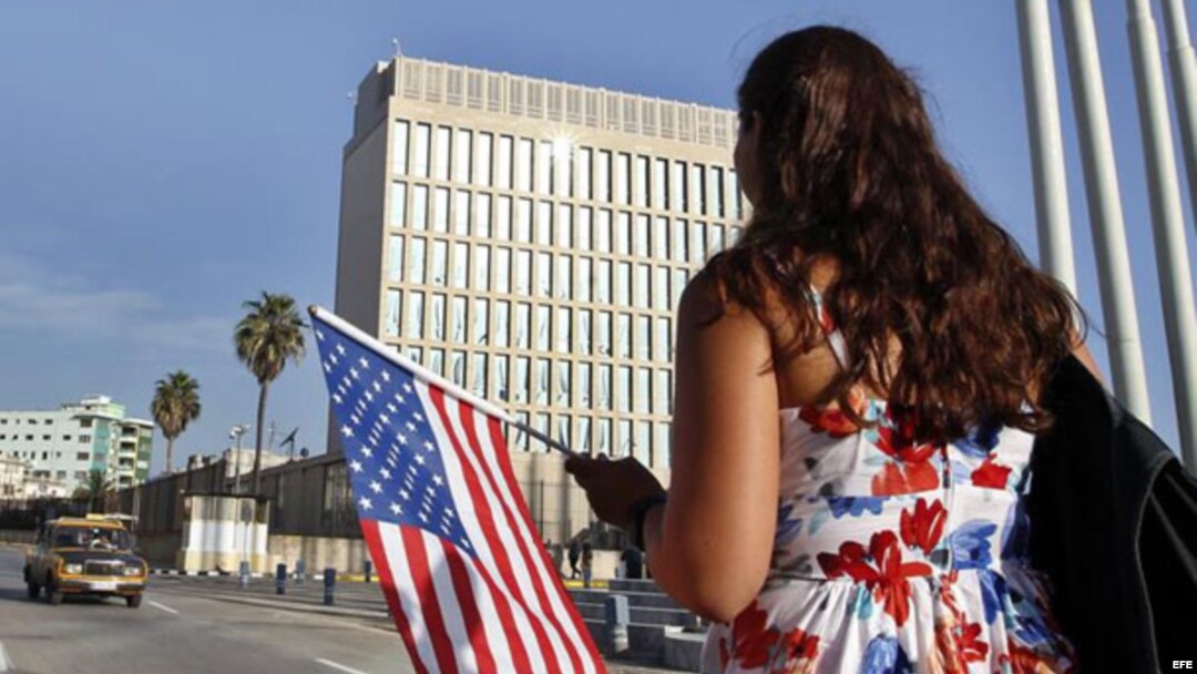 Una mujer camina con una bandera de EE.UU. frente a la embajada de ese país en La Habana
