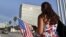 Una mujer camina con una bandera de EE.UU. frente a la embajada de ese país en La Habana