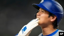 Shohei Ohtani, de los Dodgers de Los Ángeles, se quita el guante mientras camina hacia el dugout (Foto AP/Alex Brandon)