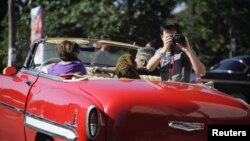 Un turista toma fotos desde un carro en La Habana.