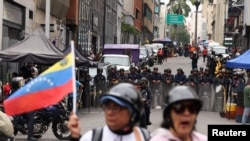 Manifestantes en Caracas protesta contra autoridades por mejoras en atención de salud frente a policías antimotines. (REUTERS)