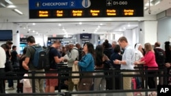 Viajeros en un punto de control en el Aeropuerto Internacional de Miami, el 23 de mayo de 2024. (AP Photo/Lynne Sladky).