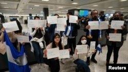 Activistas sostienen carteles con los nombres de algunos de los más de 200 presos políticos liberados de Nicaragua, mientras esperaban su llegada al Aeropuerto Internacional Dulles en Virginia, en las afueras de Washington, EEUU, el 9 de febrero de 2023. (Reuters/Kevin Lamarque).