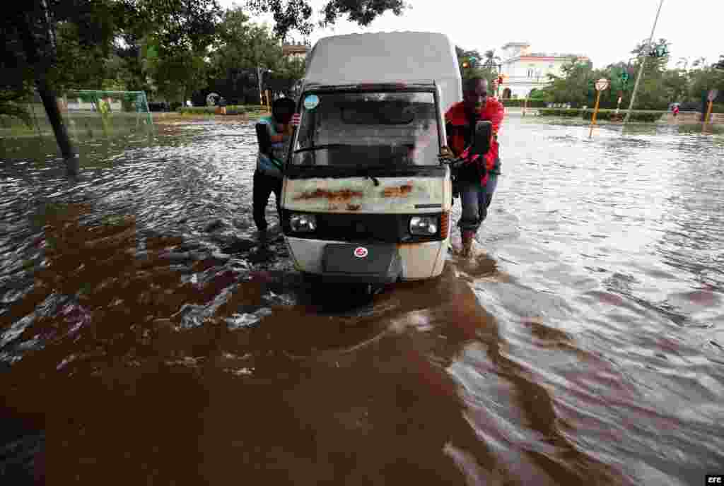 Jóvenes empujan un vehículo averiado en una calle inundada en La Habana (Cuba). 