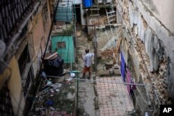 Mario Luis Poll habla con un vecino dentro de una mansión en ruinas donde viven seis familias en la calle Villegas en La Habana, Cuba, el 5 de octubre de 2023. AP/Ramón Espinosa.