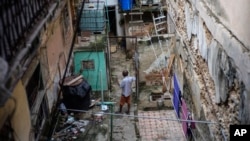 Mario Luis Poll habla con un vecino dentro de la mansión en ruinas en la calle Villegas en La Habana. (Foto AP/Ramón Espinosa)