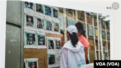 Firmantes del Acuerdo de Paz en Colombia analizan una galería fotográfica con los rostros de antiguos combatientes desaparecidos. Esta imagen de 2023 es parte de la exhibición "El Camino de la Búsqueda", presentada por el Instituto de la Paz de EEUU.